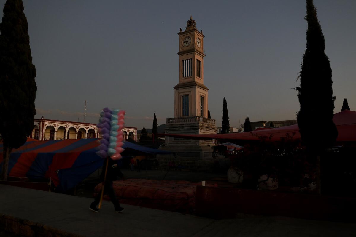 A clock tower is surrounded by an open-air market in the Plaza de la Constitucion in Tlaxiaco.