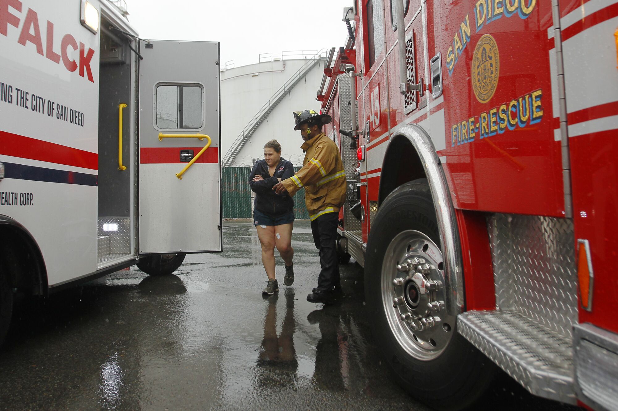 A woman is helped to an ambulance after being rescued in a flood control channel along I-15 in Mission Valley.