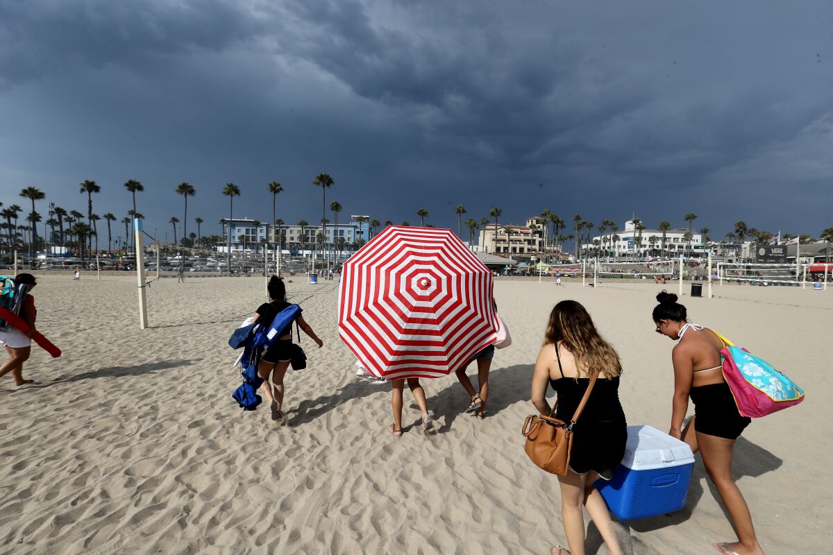 Beachgoers evacuate Huntington Beach because of potential lightning with a monsoon thunderstorm in August 2017.