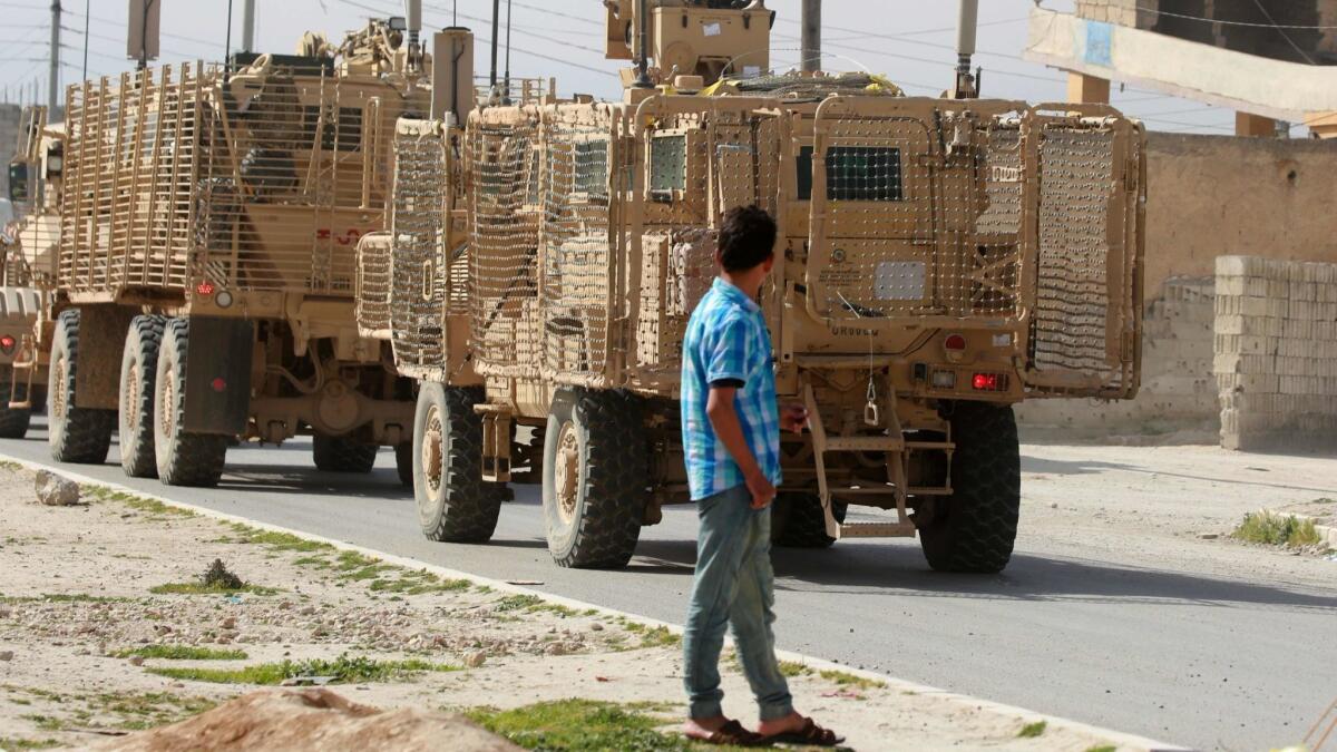 An April 3 photo shows U.S.-backed coalition forces driving in the northern Syrian town of Manbij. On the outskirts of Syria's Manbij, Kurdish-led fighters have dug trenches and U.S.-led coalition soldiers patrol from land and sky after Turkey threatened to overrun the city.