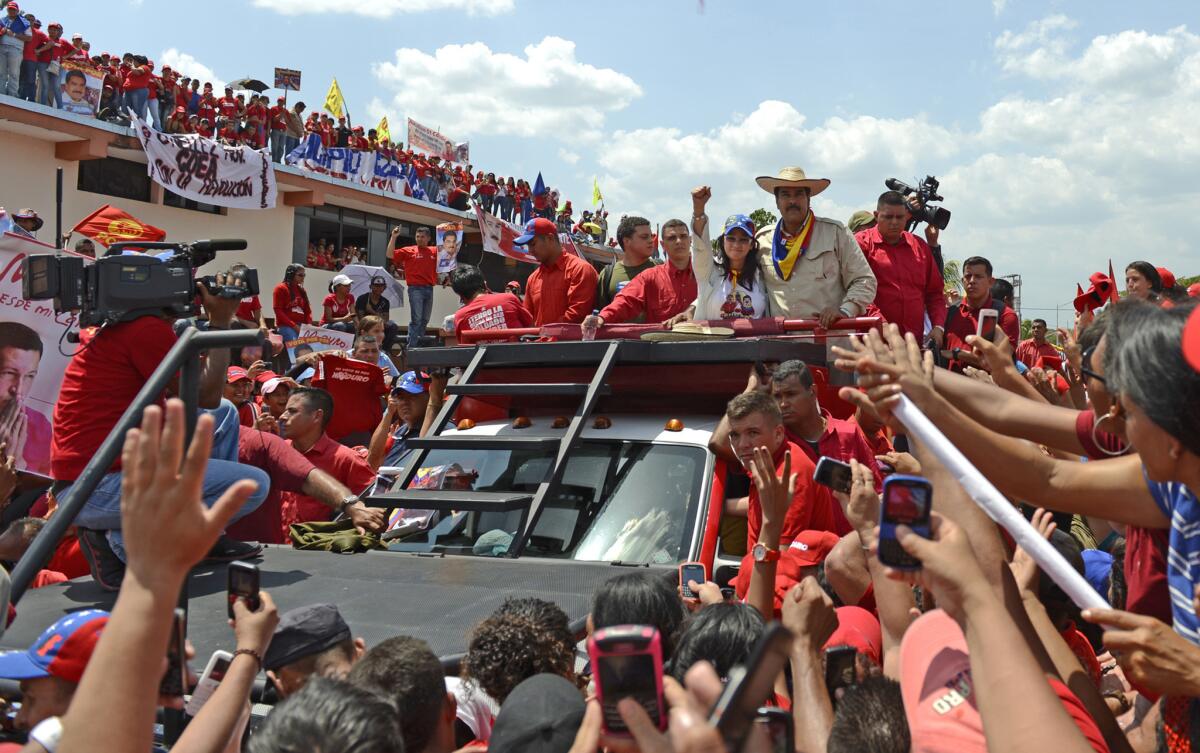 Venezuelan acting President Nicolas Maduro (center at right, with hat) and his wife Cilia Flores greet supporters during a campaign rally in San Carlos.