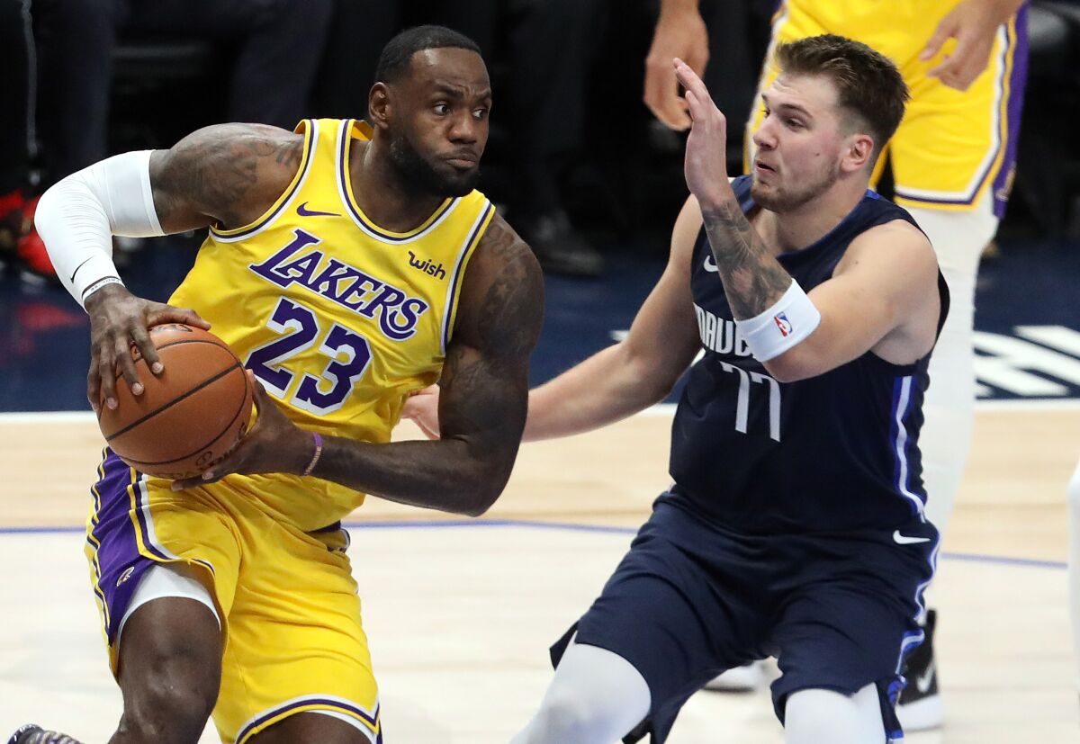 The Lakers' LeBron James dribbles the ball against the Dallas Mavericks' Luka Doncic.