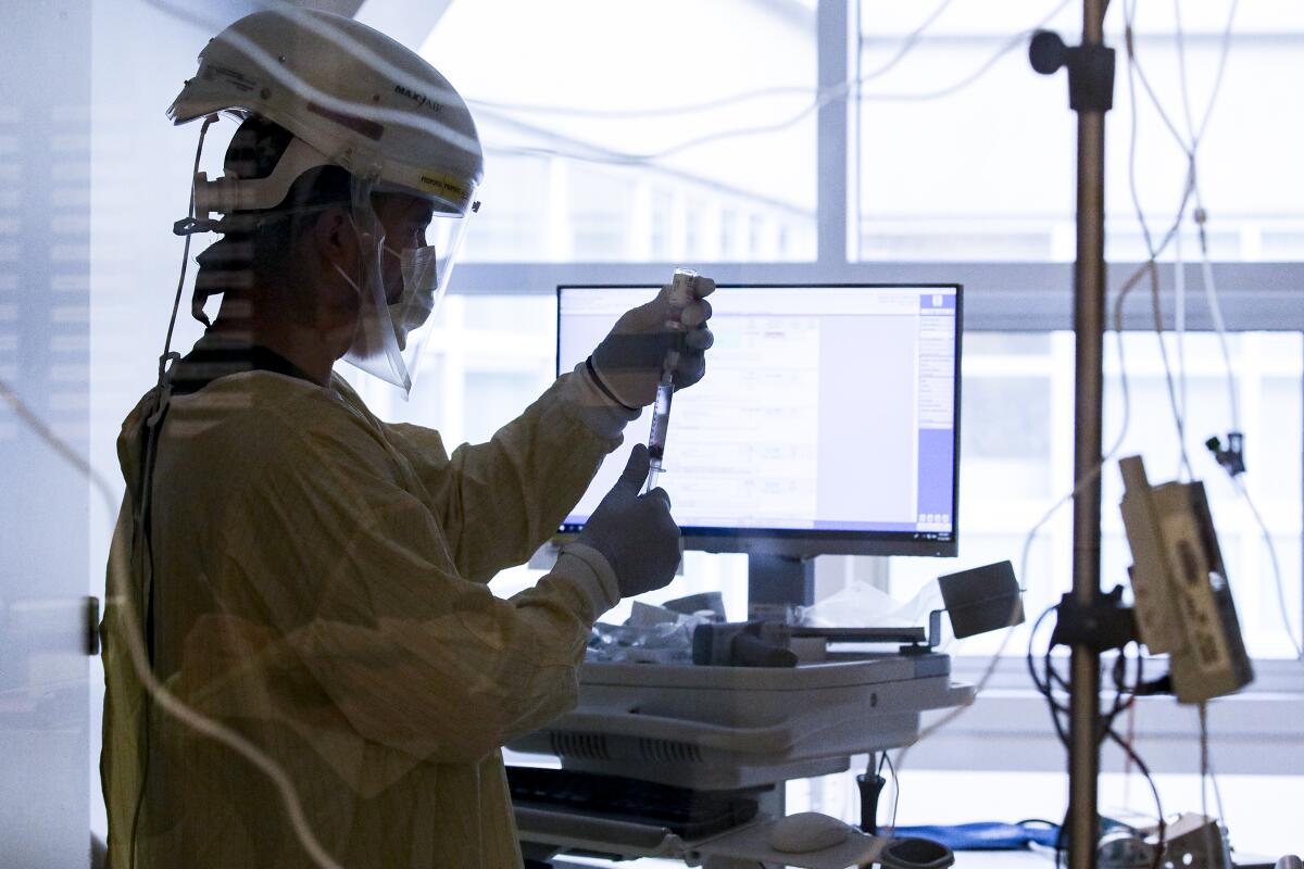 A nurse prepares medication for a COVID-19 patient.