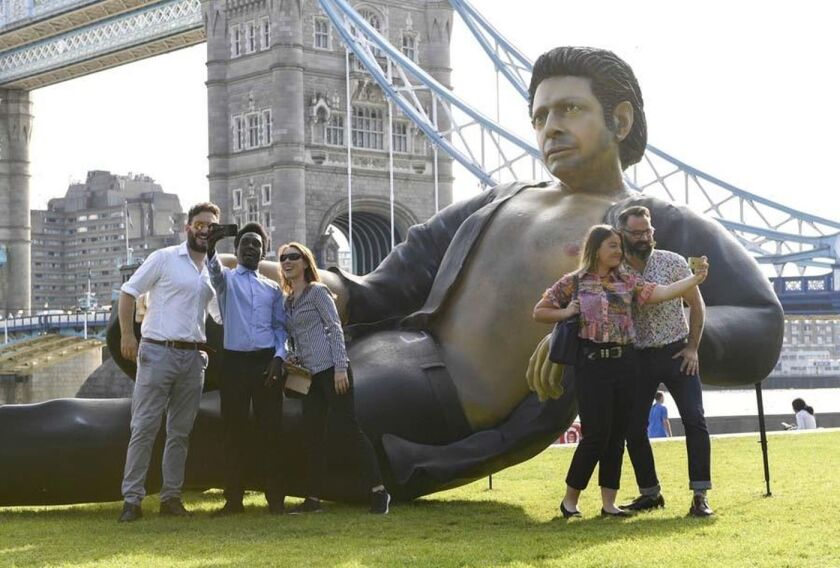 People take photos in front of a massive statue of Jeff Goldblum erected in a park near London's Tower Bridge.