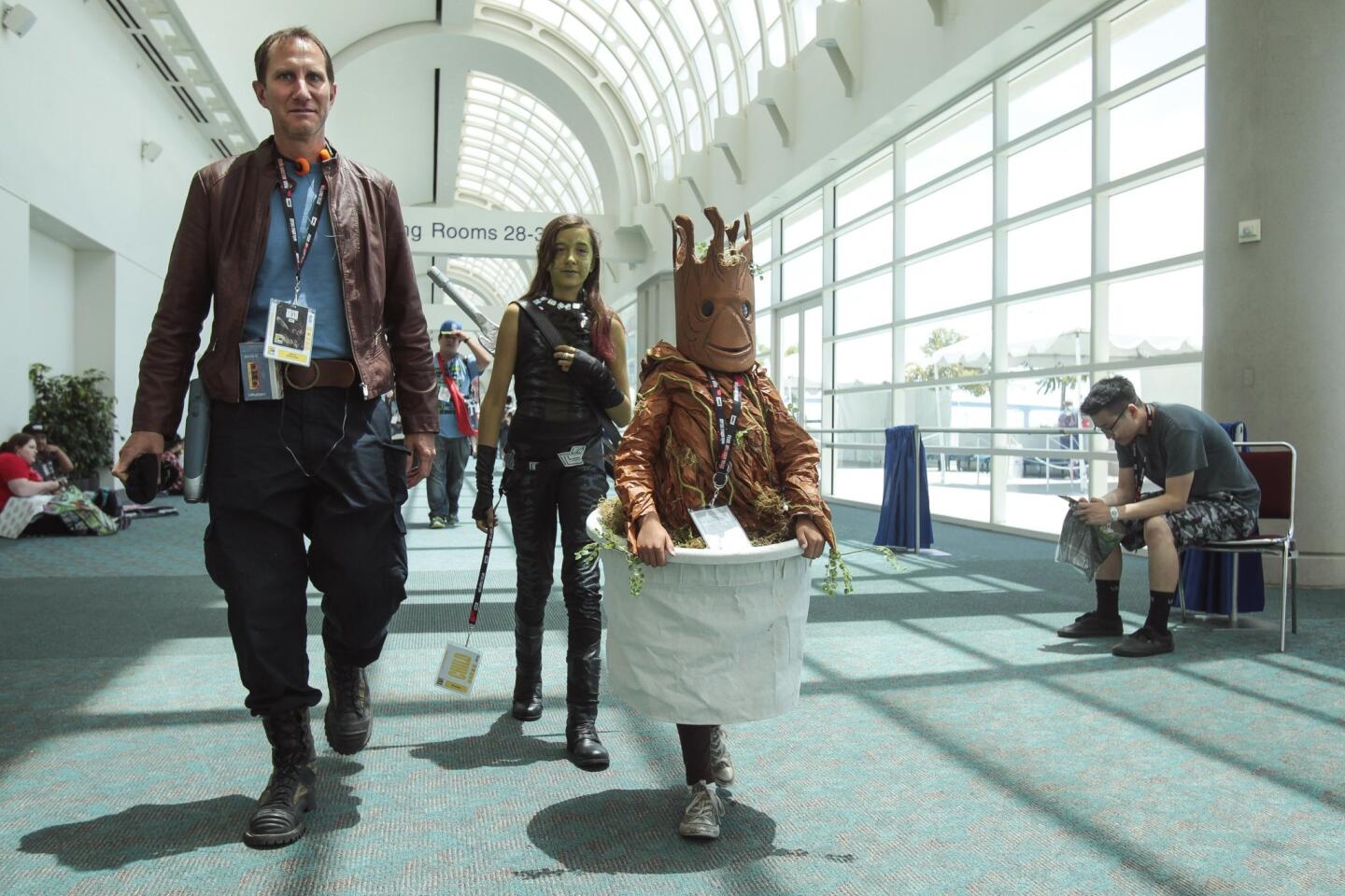 While all of the dressed as characters in the movie "Guardians of the Galaxy" Jeff Hernandez and daughters Lianna, 9, right, in a Baby Groot costume, and Gabriella, 12, dressed as Gamora, walk through the San Diego Convention Center during Comic-Con.