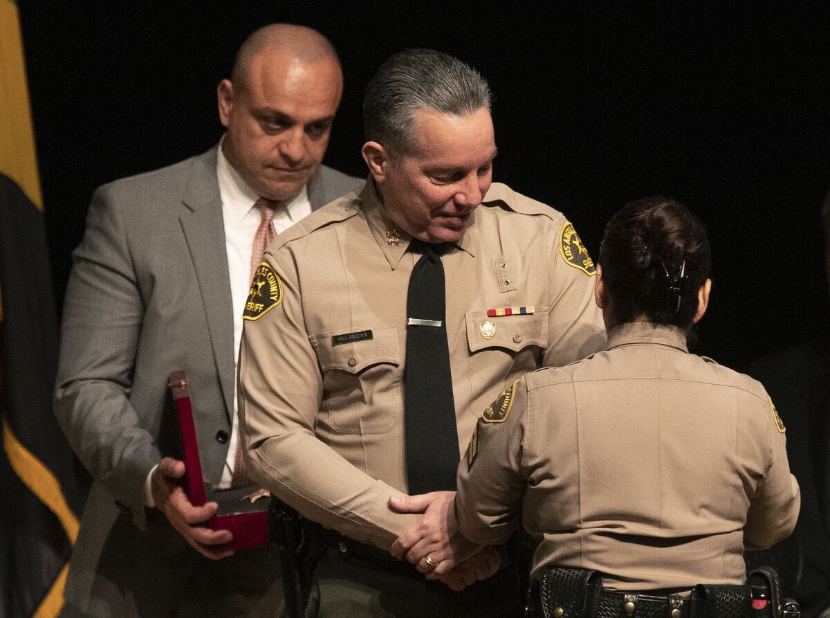 L.A. County Sheriff's Deputy Caren Carl Mandoyan, left, looks on as during the swearing-in of Sheriff Alex Villanueva. Mandoyan had been fired in connection with allegations of abuse, stalking and harassment but was reinstated by Villanueva.