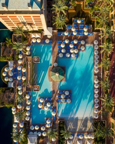 An aerial view of a pool surrounded by lounge chairs with a sand bar at the entry.