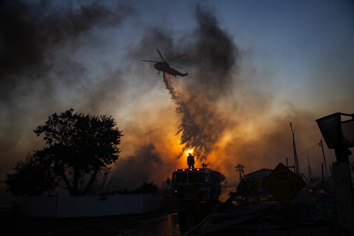 A helicopter drops water on the Villa Calimesa Mobile Home Park in Riverside County.