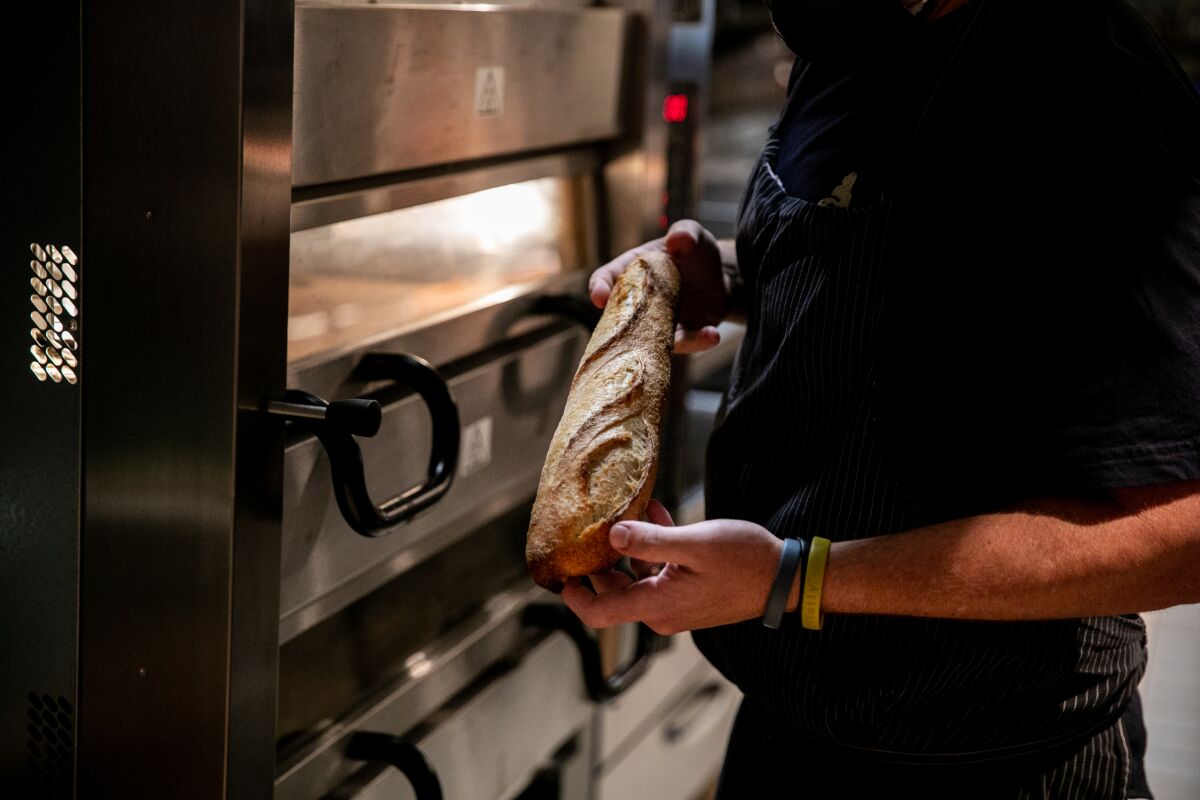Chef/owner Travis Swikard holds a house-made Kamut baguette at his new East Village restaurant Callie on May 28
