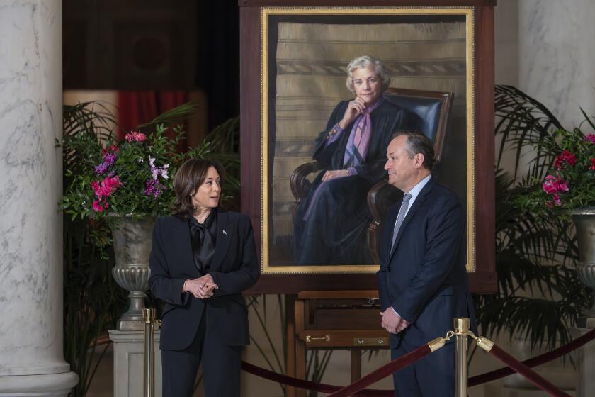 Vice President Kamala Harris, left, and first gentleman Doug Emhoff pay their respects as they walk past a portrait of retired Supreme Court Justice Sandra Day O'Connor as her casket lies in the Great Hall at the Supreme Court in Washington, Monday, Dec. 18, 2023. O'Connor, an Arizona native and the first woman to serve on the nation's highest court, died Dec. 1 at age 93. (AP Photo/J. Scott Applewhite)