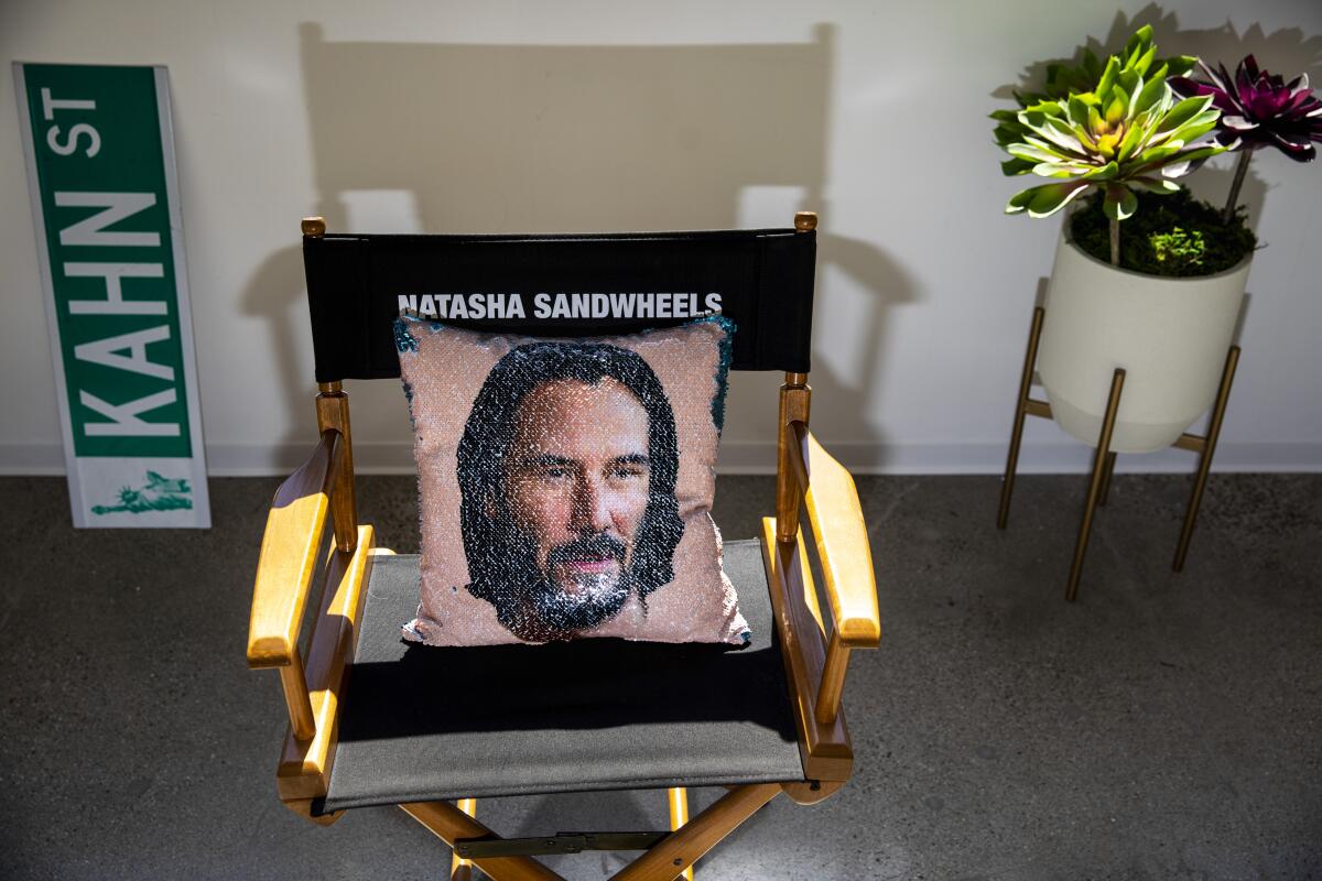 A Keanu Reeves pillow on a director's chair with the name "Natasha Sandwheels."