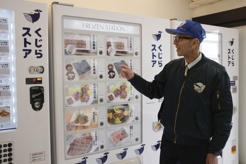 Konomu Kubo, un vocero de Kyodo Senpaku Co., explica la venta de carne de ballena en una máquina expendedora en la tienda de la empresa, el jueves 26 de enero de 2023, en Yokohama, Japón. (AP Foto/Kwiyeon Ha)