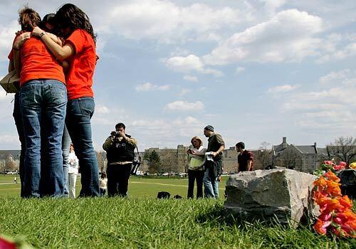 Tracy Ross, left, Jenna De Quila, and Anahita Schacht, right, cry and comfort one another in front of a makeshift memorial on the Virginia Tech drill field.