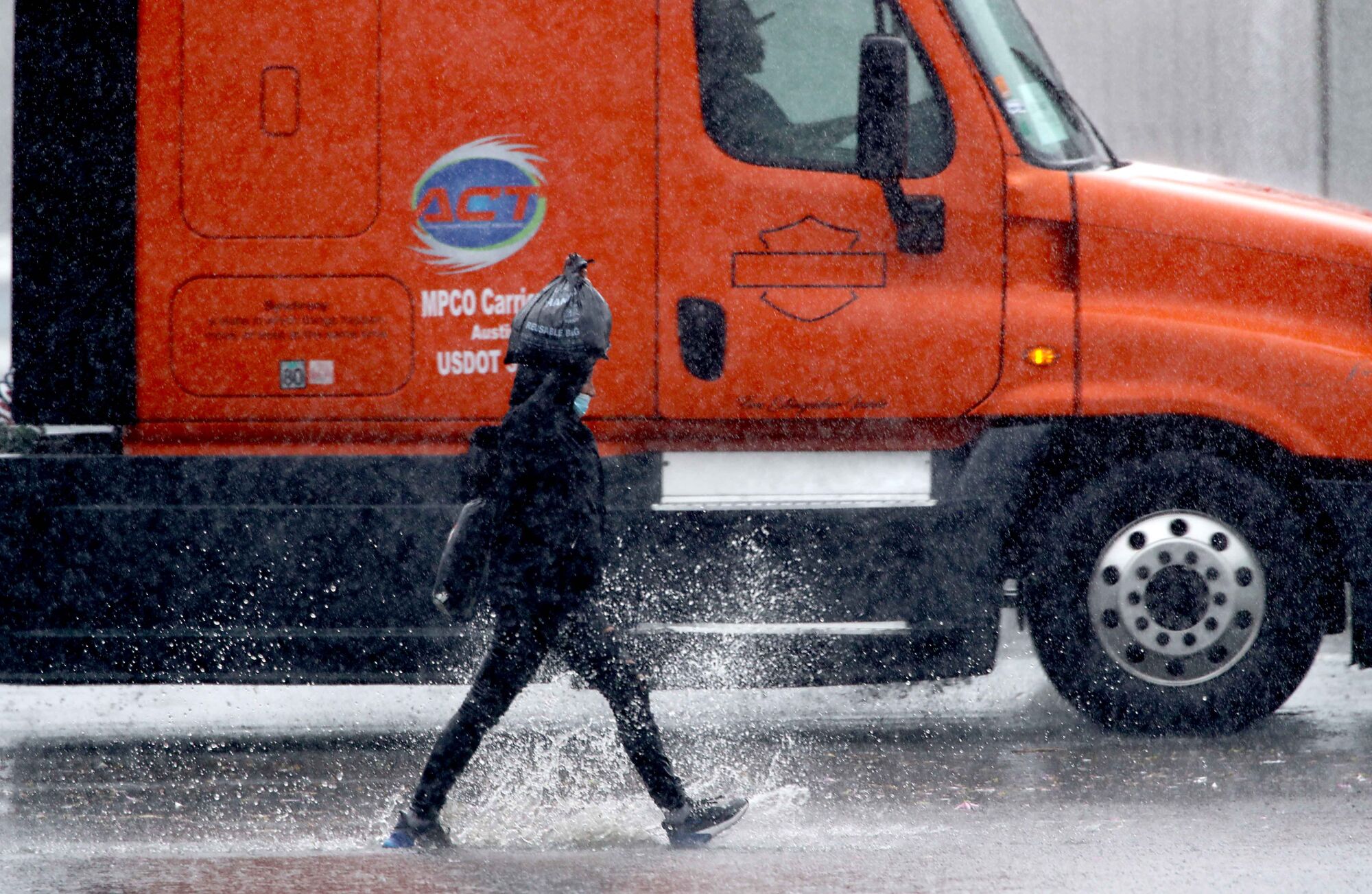 A pedestrian splashes next to a truck.