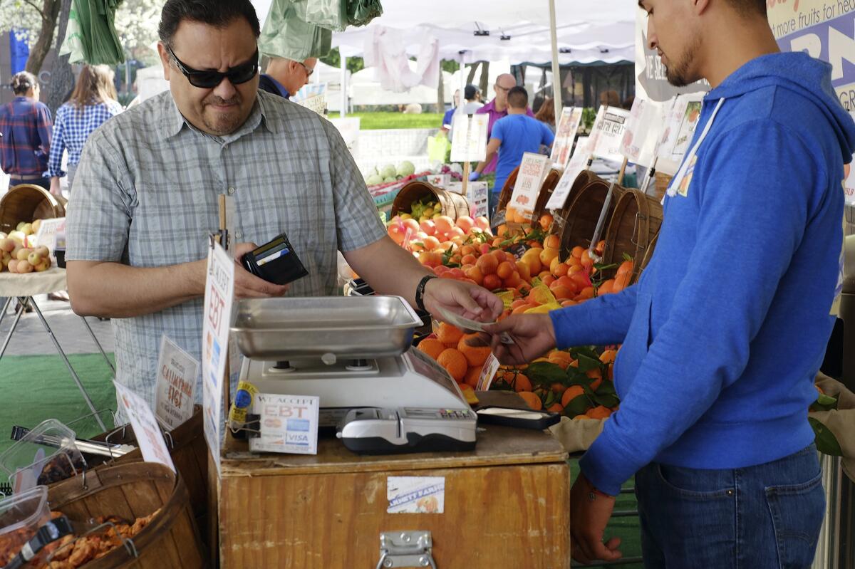 Fotografía de archivo del 6 de febrero de 2015 de un comprador pagando frutas en un mercado en el centro de Los Ángeles. (Foto AP/Richard Vogel, Archivo)