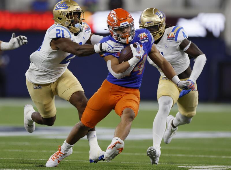 Boise State running back George Holani breaks away from UCLA's JonJon Vaughns and Carl Jones Jr. in the first half.