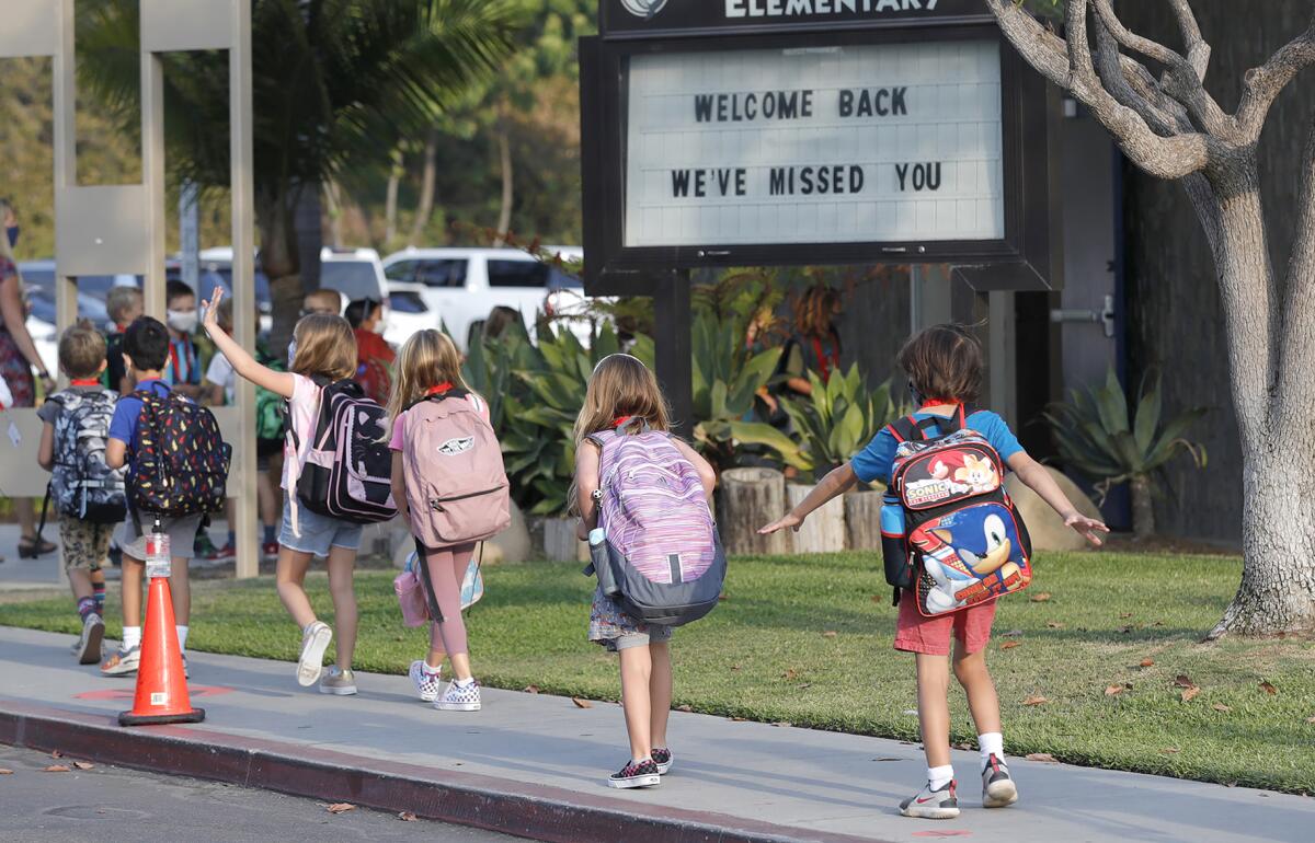 Kindergartners walk past a marquee sign welcoming them back to Top of the World Elementary School.