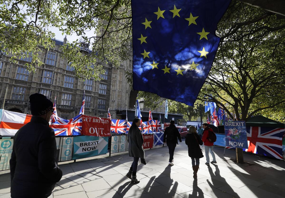 Pedestrians walk past a European Union flag outside Parliament in London.