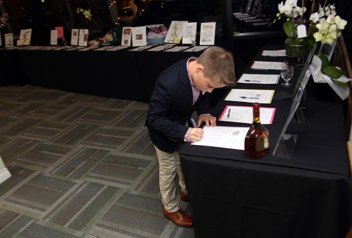 A boy makes a bid at the silent auction during the annual fundraiser "An Evening of Wine and Roses" for La Cañada's float in the 2020 Rose Parade.