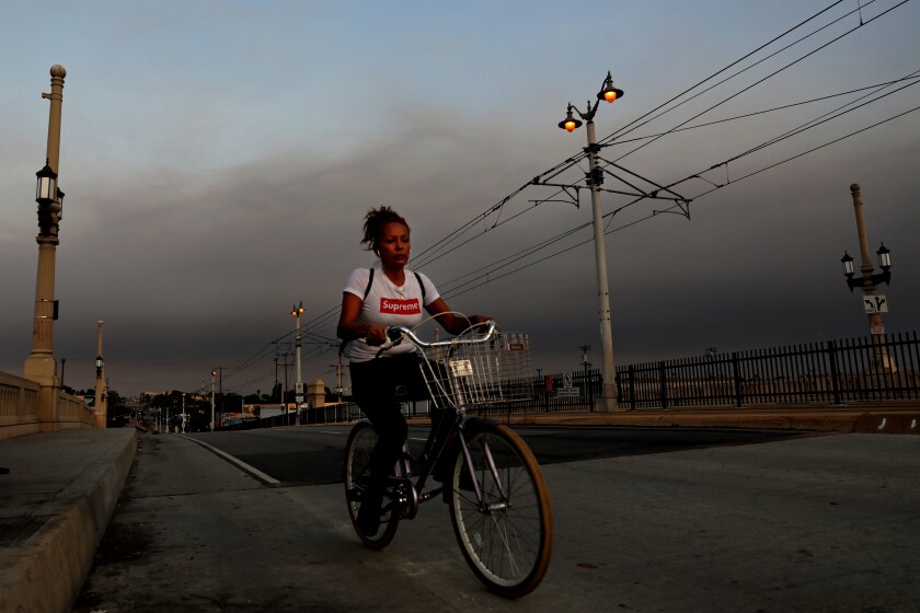 A bicyclist rides along the 1st Street Bridge as a layer of smoke hovers east of downtown in Los Angeles.
