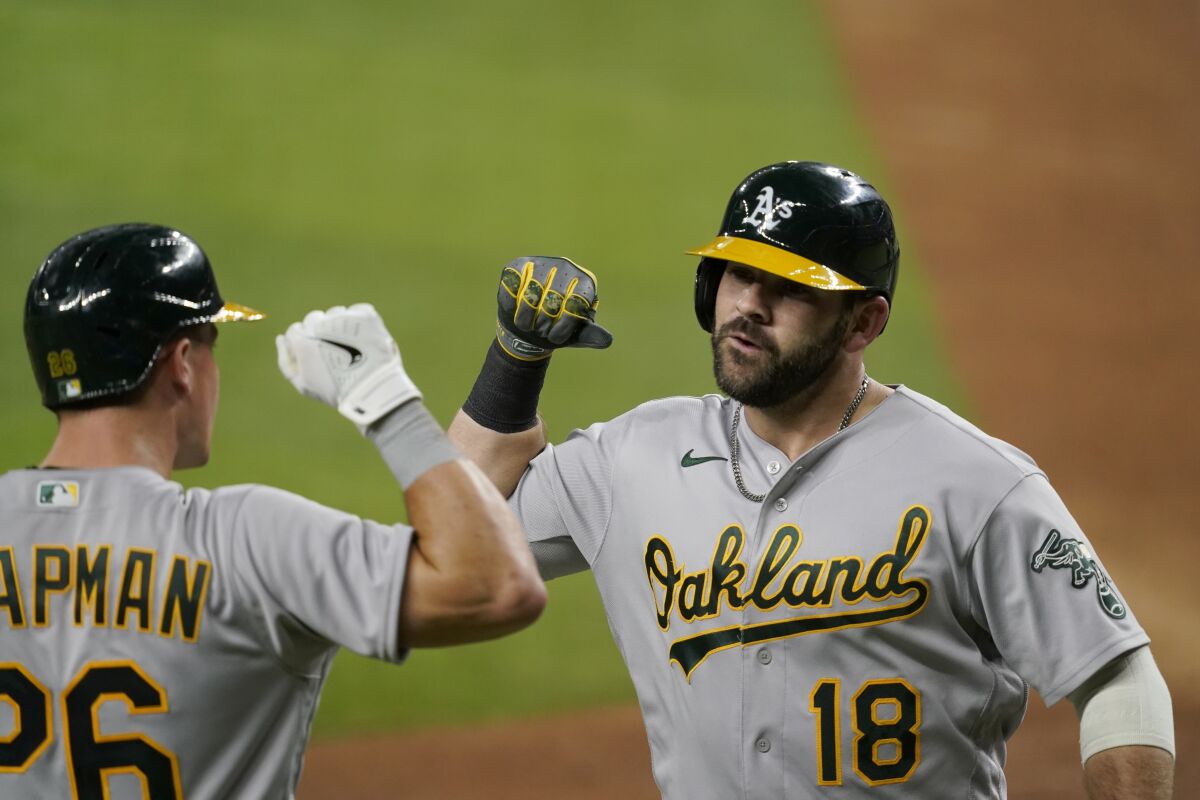 Oakland Athletics' Matt Chapman (26) and Mitch Moreland (18) celebrate after Moreland hit a solo home run in the seventh inning of the team's baseball game against the Texas Rangers in Arlington, Texas, Saturday, Aug. 14, 2021. (AP Photo/Tony Gutierrez)