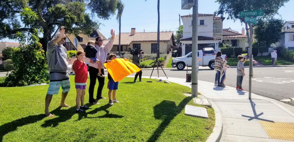 The Gaydet family holds a sign and waves to Loma Portal Elementary School teachers driving by.