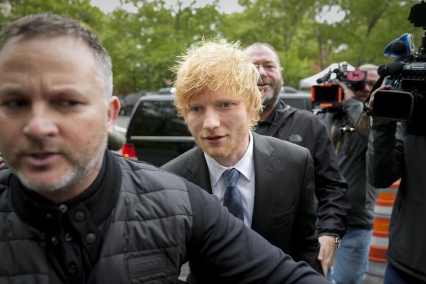 Ed Sheeran in a suit surrounded by bodyguards