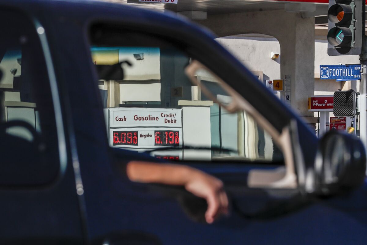 The sign at a gas station, seen through a vehicle window, displays a $6.09 cash price.
