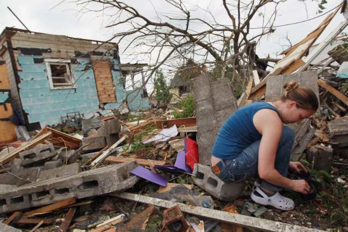 Chrystal Wilcox collects coins that she found on the ground next to her home after it was destroyed when a massive tornado passed through the town killing at least 116 people in Joplin, Missouri. Authorities were prepared to find more bodies in the town of 50,000 people.