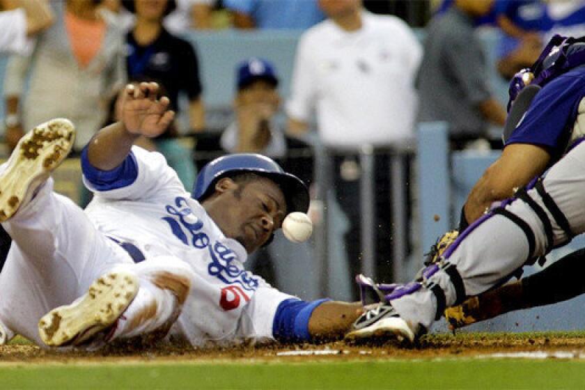 Juan Uribe slides safely into home as Colorado catcher Wilin Rosario loses the ball during the Dodgers' 6-1 victory over the Rockies on Thursday.