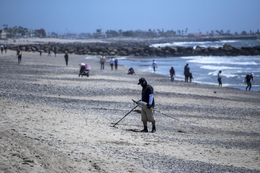 VENTURA, CA - MAY 02: A man hunts for treasure with a metal detector on a wide open but restricted San Buenaventura State Beach on Saturday, May 2, 2020 in Ventura, CA. (Brian van der Brug / Los Angeles Times)