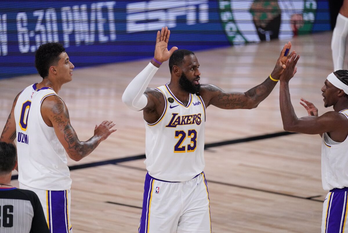 Los Angeles Lakers' LeBron James (23) celebrates with teammates Kyle Kuzma, left, and Rajon Rondo, right, during the second half of an NBA conference semifinal playoff basketball game against the Houston Rockets Tuesday, Sept. 8, 2020, in Lake Buena Vista, Fla. The Lakers won 112-102. (AP Photo/Mark J. Terrill)