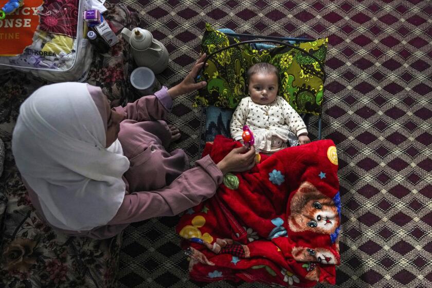 Rola Saqer sits beside her baby Masa Mohammad Zaqout in Zawaida, central Gaza, April 4, 2024. Zaqout was born Oct. 7, the day the Israel-Hamas war erupted. Mothers who gave birth in the Gaza Strip that day fret that their 6-month-old babies have known nothing but brutal war, characterized by a lack of baby food, unsanitary shelter conditions and the crashing of airstrikes. (AP Photo/Abdel Kareem Hana)