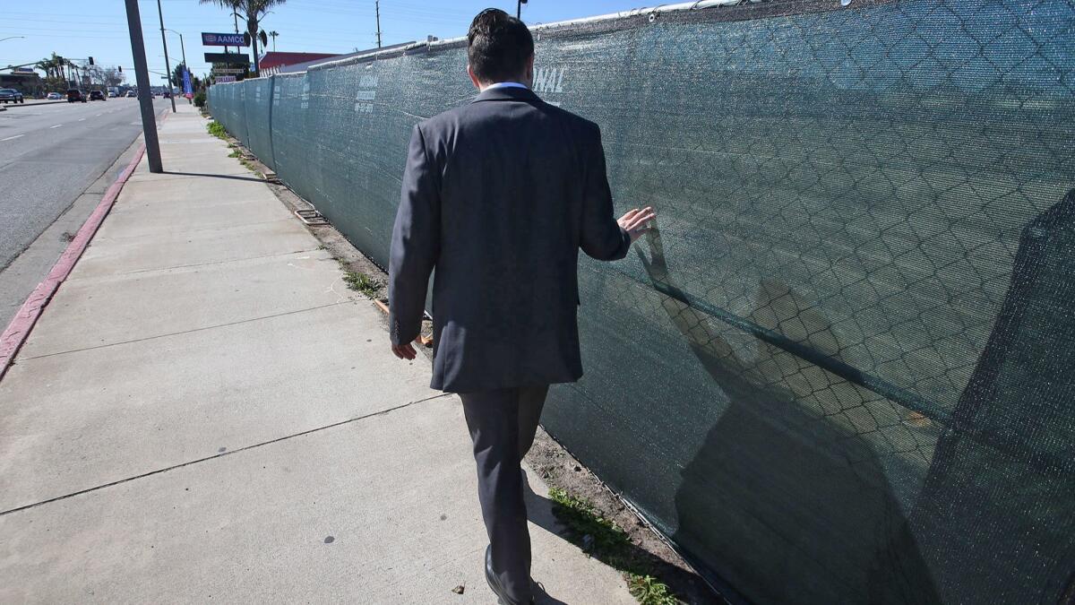 Dilan Oezkan walks along the fence, remembering what it was like to live in the now torn down Costa Mesa Motor Inn property in Costa Mesa. He was able to fight his way out of poverty and get his own apartment. He will soon attend college.