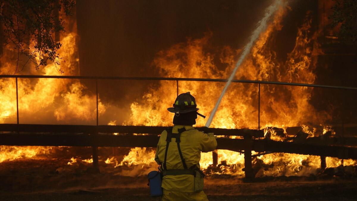 A firefighter battles flames spreading at a Keysight Technologies building in Santa Rosa, Calif.