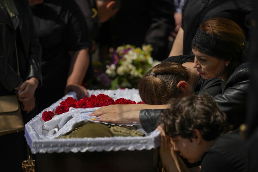 Iuliia Loseva, right, and her sons Hryhorii and Denys cry over the coffin of their husband and father Volodymyr Losev, 38, during his funeral in Zorya Truda, Odesa region, Ukraine, Monday, May 16, 2022. Volodymyr Losev, a Ukrainian volunteer soldier, was killed May 7 when the military vehicle he was driving ran over a mine in eastern Ukraine. (AP Photo/Francisco Seco)