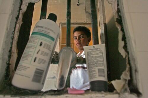 SUBSTANDARD: Mario del Rio looks through a hole in his shower. The building was built in 1904 as a residential hotel