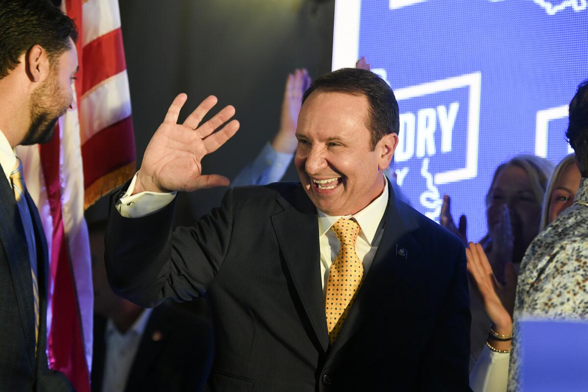 A man smiles and waves at an election party. 