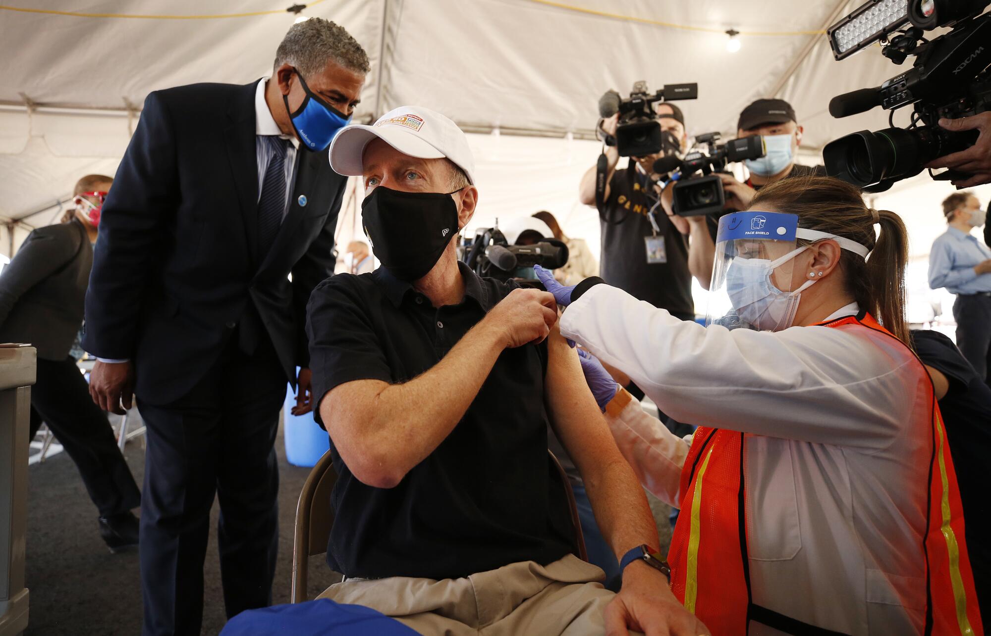 Austin Beutner receives a shot inside a tent.