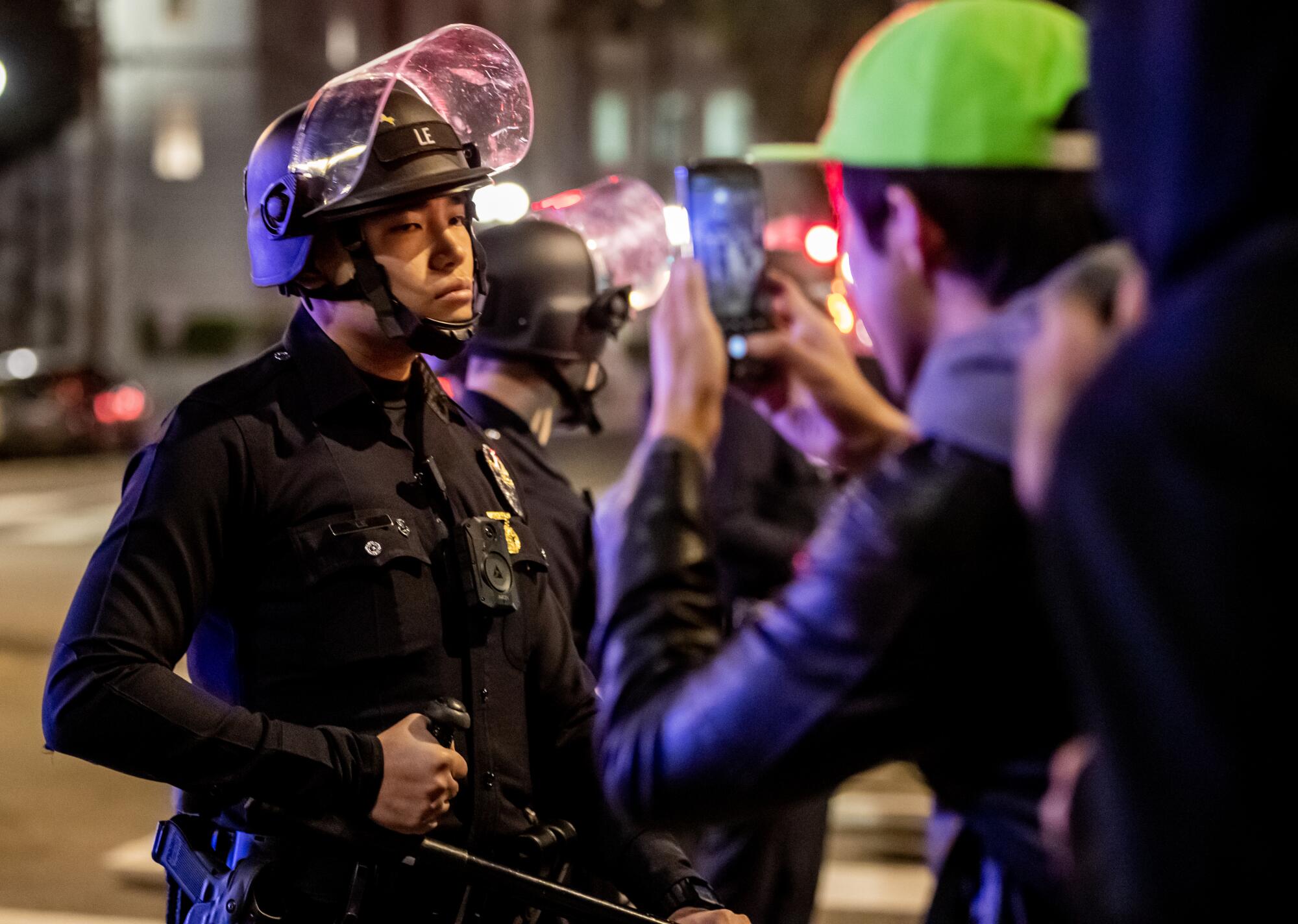 A protester confronts Los Angeles Police officers wearing riot gear.
