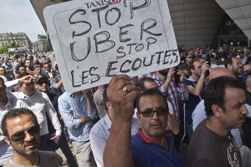 A taxi driver in France holds a placard that reads, "Stop Uber, Stop listening," referring to the new U.S. spying report in France, during a taxi drivers demonstration in Paris.