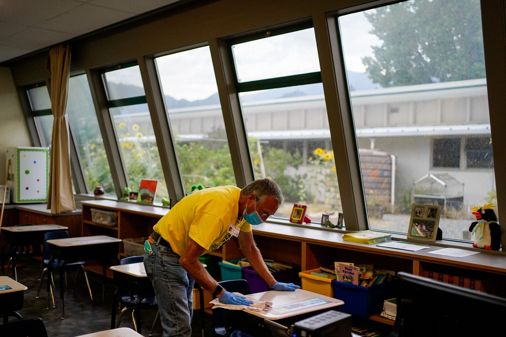 Maintenance worker Larry Horrocks disinfects desks at Weaverville Elementary School.