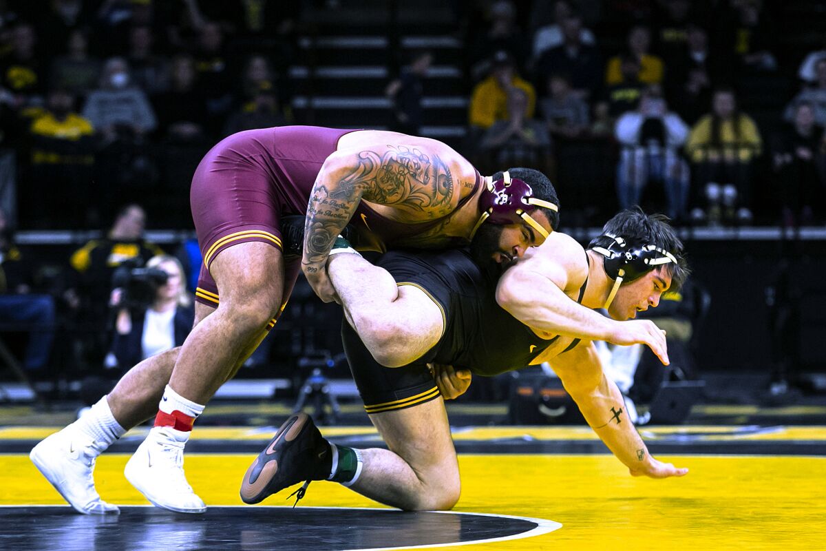 FILE - Minnesota's Gable Steveson, left, competes with Iowa's Tony Cassioppi at 285 pounds during a college wrestling dual Friday, Jan. 7, 2022, in Iowa City, Iowa. Gable Steveson knew his life had changed after he won an Olympic gold medal in wrestling. But the University of Minnesota star remains shocked by how fans have celebrated him this season during what has amounted to a college farewell tour. (Jospeh Cress/Iowa City Press-Citizen via AP, File)