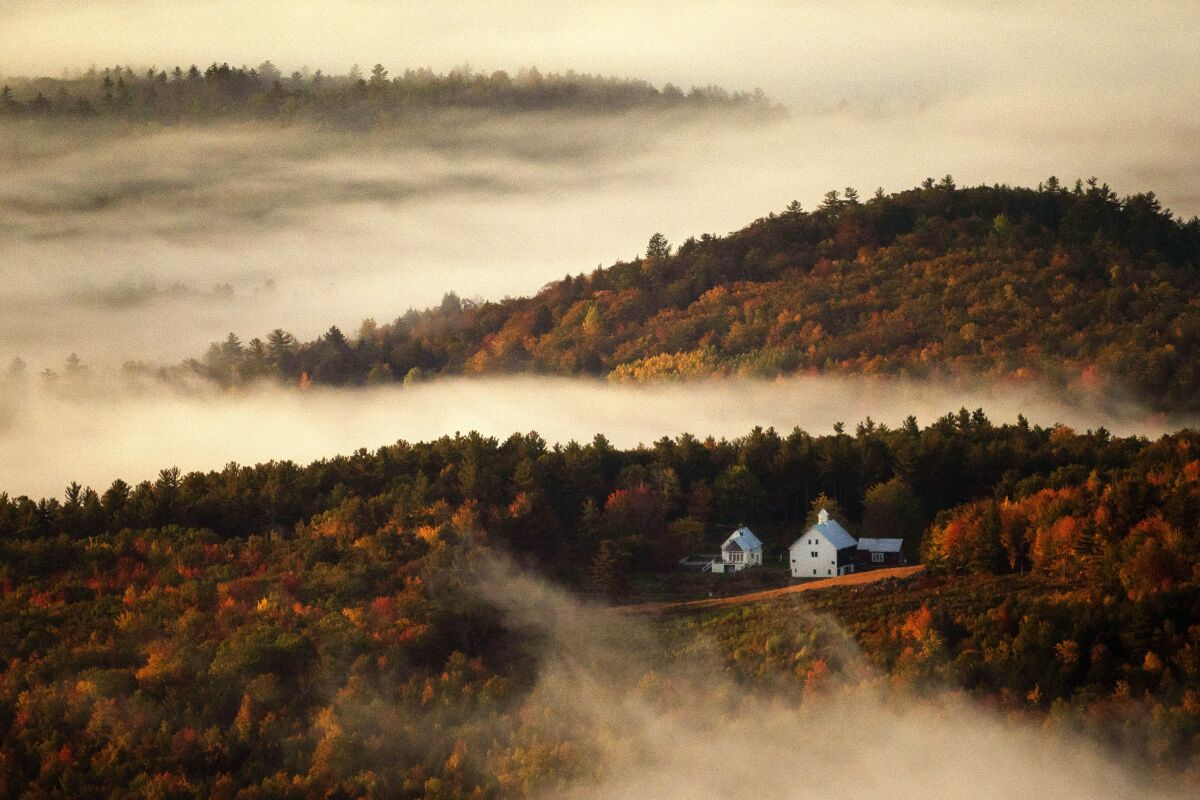 Valley fog wafts through the autumn-colored hills near the Picket Hill Farm, Wednesday morning, Oct. 13, 2021, in Denmark, Maine. The farm complex was built in the 1830s. (AP Photo/Robert F. Bukaty)