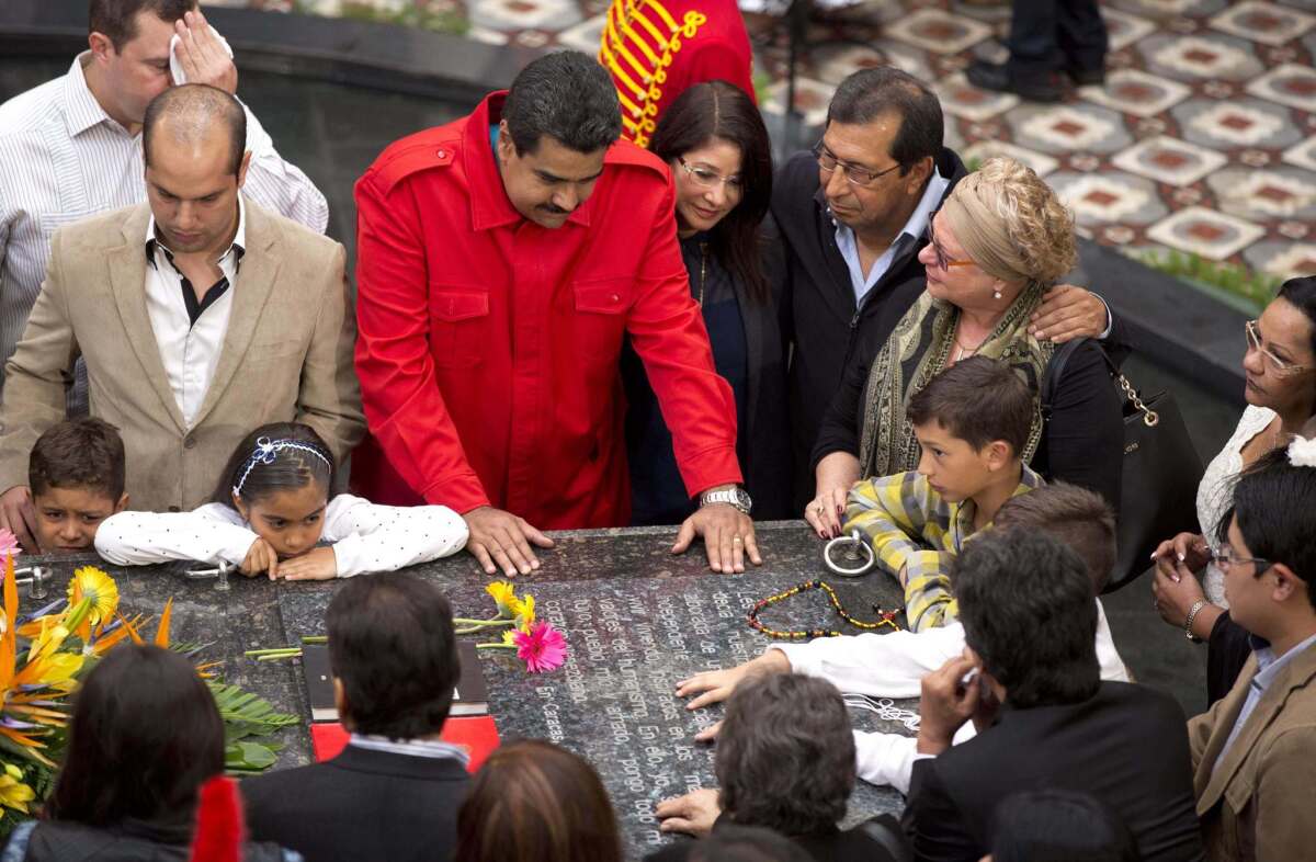 Venezuelan President Nicolas Maduro, center, gathers at the tomb of late President Hugo Chavez with Chavez's family and government officials to mark the second anniversary of Chavez's death.