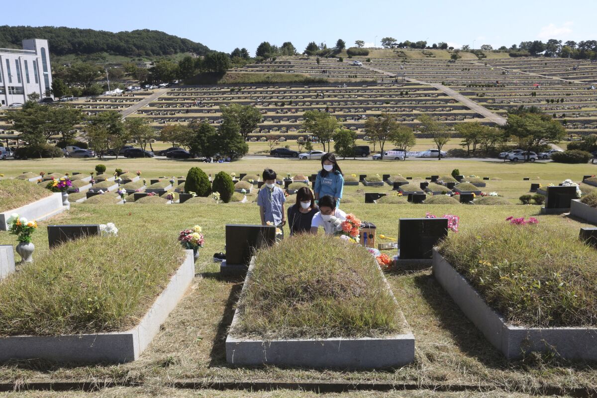A family gathers at a grave in a cemetery.