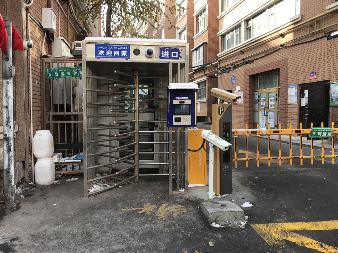 Access to a residential compound in Ürümqi is controlled by turnstiles, a facial recognition system and guards inside.