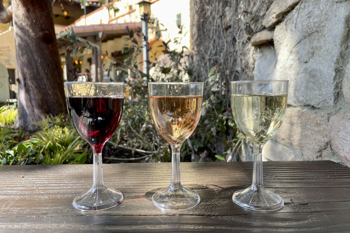 Glasses of red, rose and white wines on a wooden table outdoors at Mendocino Terrace.