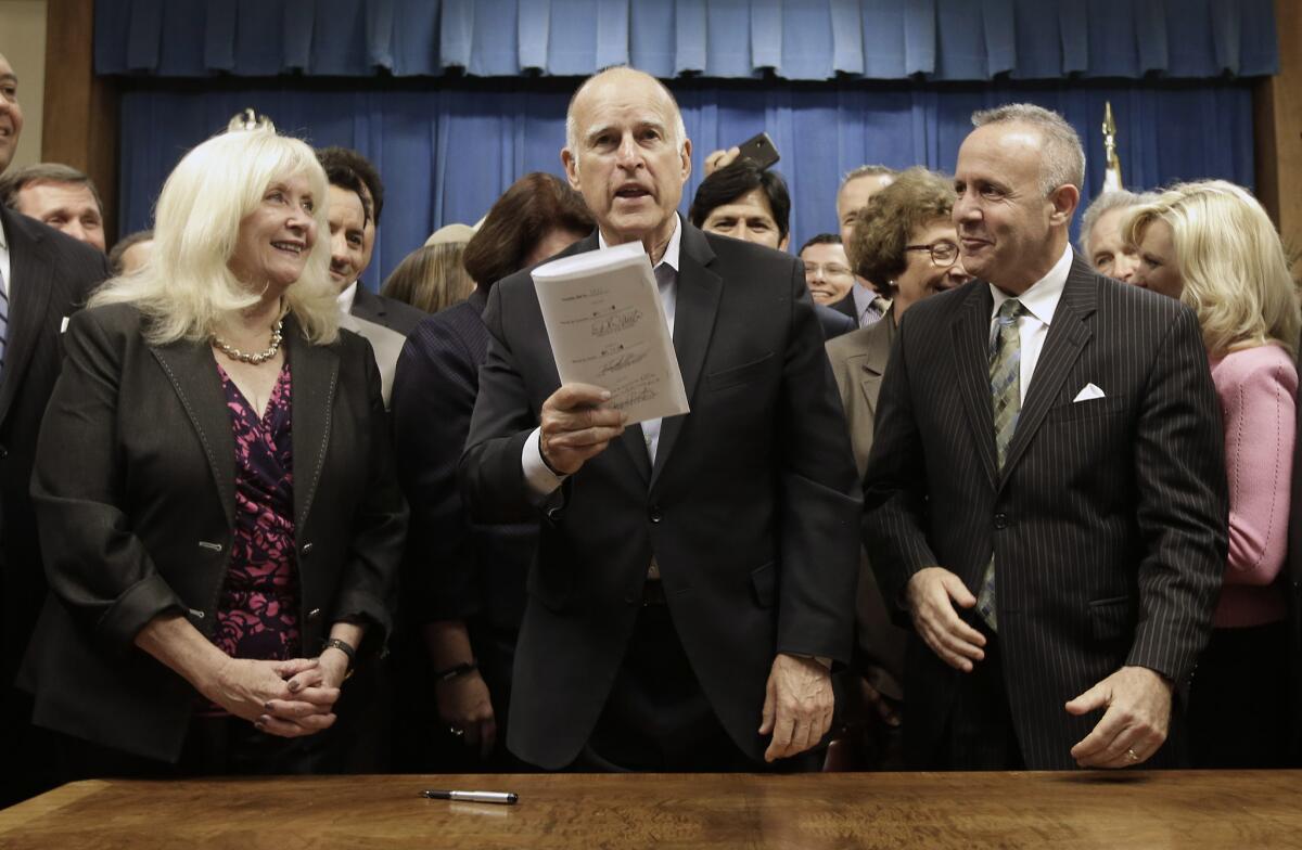 Gov. Jerry Brown, flanked by Assemblywoman Connie Conway (R-Tulare), left, and former Senate President Pro Tem Darrell Steinberg (D-Sacramento), holds up the measure he signed to place a $7.5-billion water plan on the November ballot.