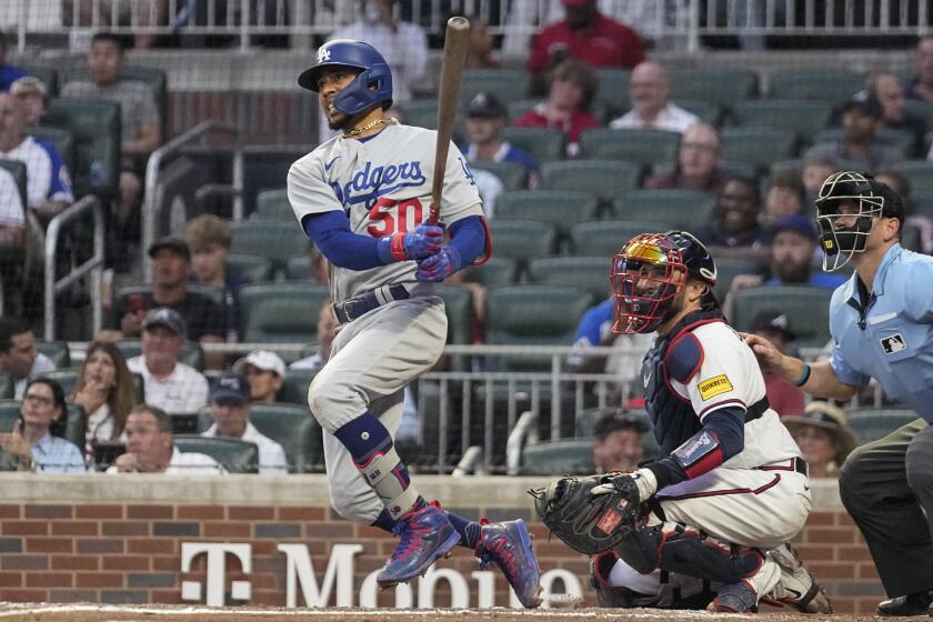 Los Angeles Dodgers' Mookie Betts watches his home run next to Atlanta Braves catcher Travis d'Arnaud during the sixth inning of a baseball game Wednesday, May 24, 2023, in Atlanta. (AP Photo/John Bazemore)